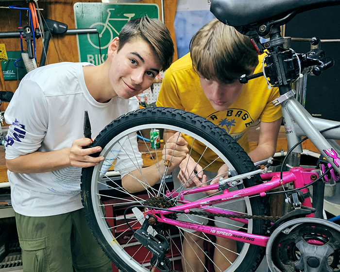 Two young men working on a bicycle.