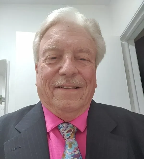 A man in a suit and tie smiling for the camera.